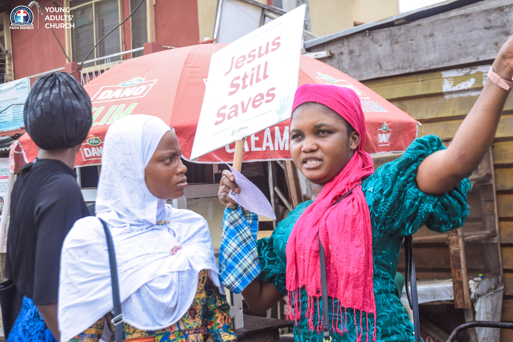 Church on the Street team evangelising in a busy marketplace with a Jesus Saves placard