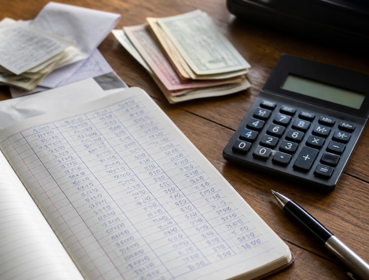 Finance desk with an accounting ledger, calculator, receipts and cash